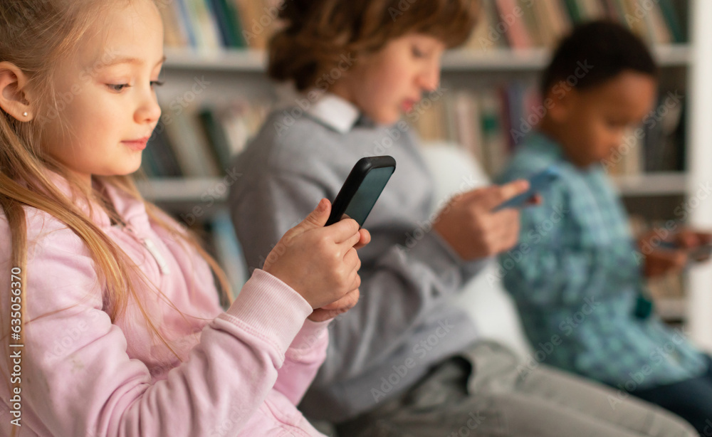 Modern caucasian schoolgirl chatting on her smartphone during break after classes in classroom at elementary school Modern caucasian schoolgirl chatting on her smartphone during break after classes in classroom at elementary school