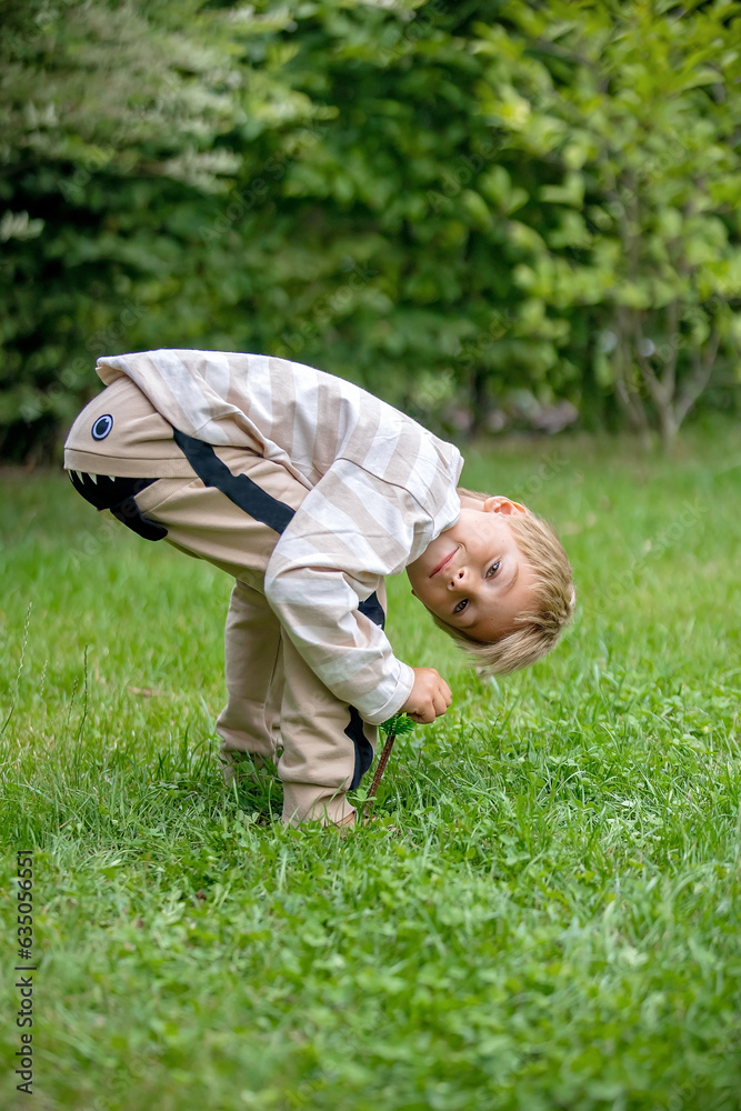 Little preschool child, with funny cloths, making smile face, looking upside down between his legs Little preschool child, with funny cloths, making smile face, looking upside down between his legs