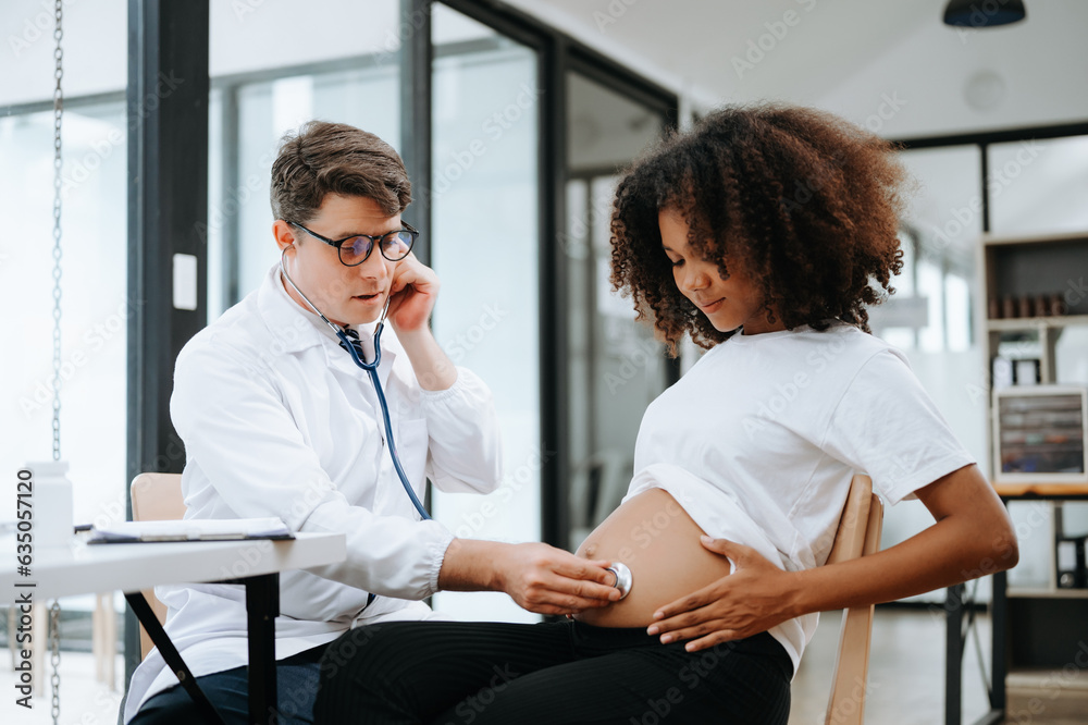 Pregnant african woman has appointment with doctor at clinic. Male gynaecologist OB GYN medic specialist with stethoscope listens to baby's heartbeat in mother's belly. Pregnancy, health care . Pregnant african woman has appointment with doctor at clinic. Male gynaecologist OB GYN medic specialist with stethoscope listens to baby's heartbeat in mother's belly. Pregnancy, health care .