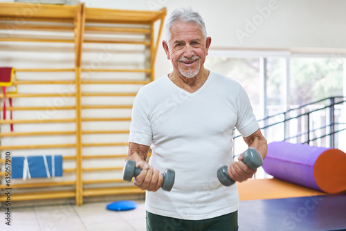 Happy elderly man exercising with dumbbells at rehab center