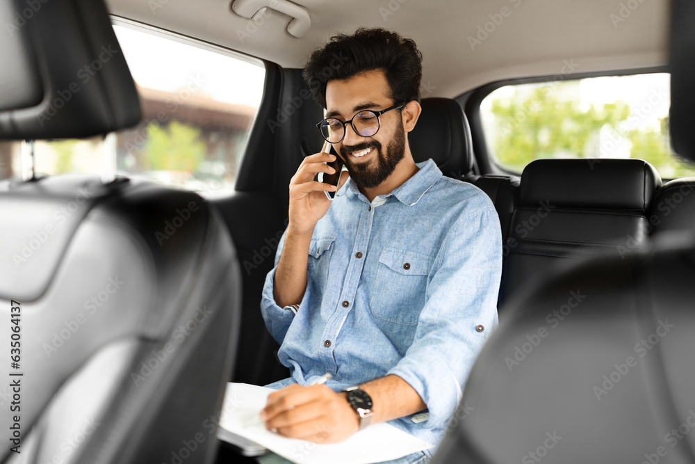 Happy young indian businessman talking over phone, sitting in taxi Happy young indian businessman talking over phone, sitting in taxi