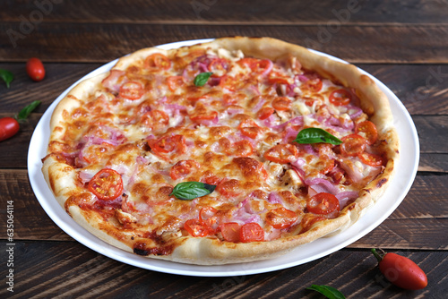 Italian pizza with ham, chicken, tomatoes and cheese.