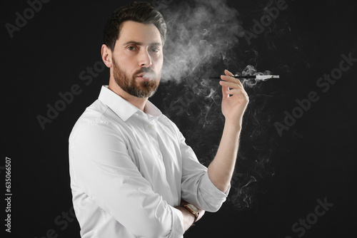 Man using long cigarette holder for smoking on black background, space for text