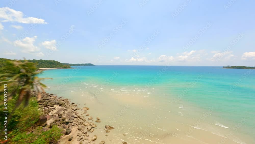 FPV drone flying close to palm trees on a tropical white sand beach with turquoise water in Thailand.