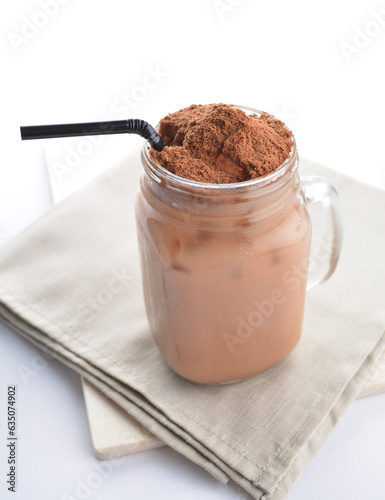 Fotografie cold iced chocolate milk milo dinosaur with coco powder in glass black straw on