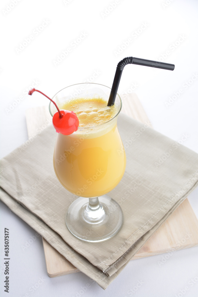 cold iced summer orange mango fruit juice with red cherry in cocktail glass black straw on grey cloth white background asian beverage halal food drink menu for hotel bar cafe cold iced summer orange mango fruit juice with red cherry in cocktail glass black straw on grey cloth white background asian beverage halal food drink menu for hotel bar cafe