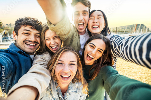 Multicultural group of friends taking selfie picture outside - Happy young people smiling at camera together - Friendship concept with guys and girls hanging in city street - Bright filter