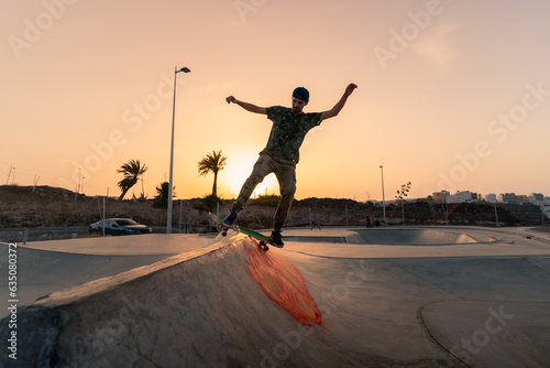 young man skates in a skate park at sunset