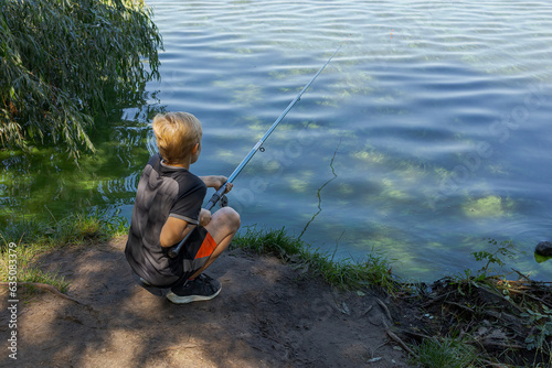 A teenager holds a fishing rod and watches a fish nibble. Sport fishing on the river in summer.