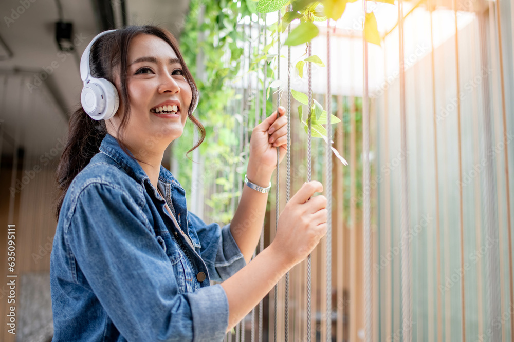 Happy woman wearing jean shirt on holiday at coffee corner listening music from Bluetooth earphone is business relaxing concept. Happy woman wearing jean shirt on holiday at coffee corner listening music from Bluetooth earphone is business relaxing concept.