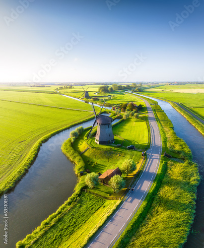 A drone view of windmills in Holland. Windmills on the banks of canals. Agricultural fields and pastures. Aerial view. Summer landscape in the Netherlands.
