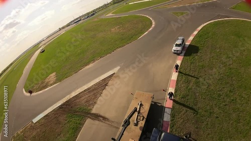 aerial filming of a circuit race on an asphalt circuit, fpv drone, racing cars go fast, time trials, sharp turns