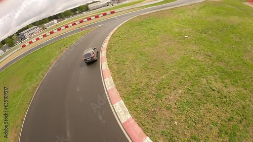 aerial filming of a circuit race on an asphalt circuit, fpv drone, racing cars go fast, time trials, sharp turns 