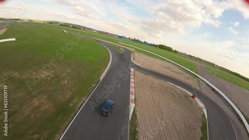 aerial filming of a circuit race on an asphalt circuit, fpv drone, racing cars go fast, time trials, sharp turns