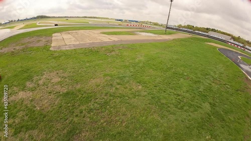 aerial filming of a circuit race on an asphalt circuit, fpv drone, racing cars go fast, time trials, sharp turns