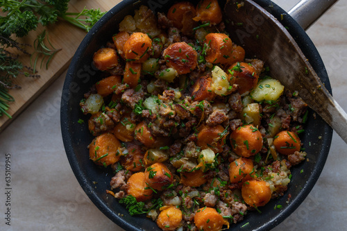 Pan fried vegetables and potatoes with ground pork in a hot frying pan. Top view