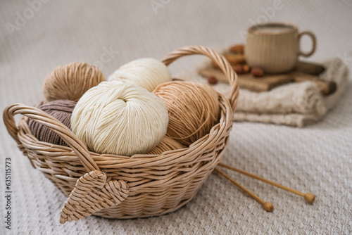 A wicker basket with yarn and a cup of coffee on the bed. Hygge lifestyle, cozy mood. Handicraft day concept