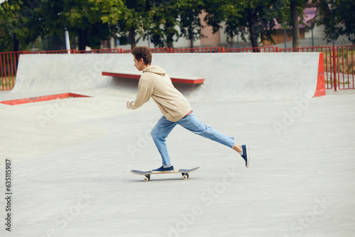 Teen boy in casual clothes skateboarding in skate park, outdoors, having fun with friends. Concept of youth culture, sport, dynamic, extreme, hobby, action and motion, friendship