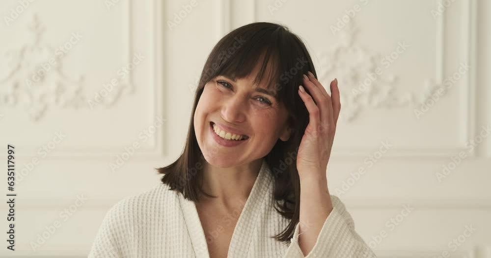 Smiling Caucasian woman in a robe looks directly at the camera. Her bright smile exudes joy and warmth, conveying a sense of happiness and approachability. Smiling Caucasian woman in a robe looks directly at the camera. Her bright smile exudes joy and warmth, conveying a sense of happiness and approachability.