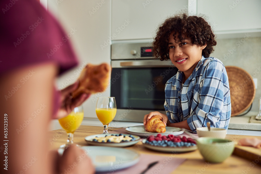 African American teenager having delicious breakfast at home.