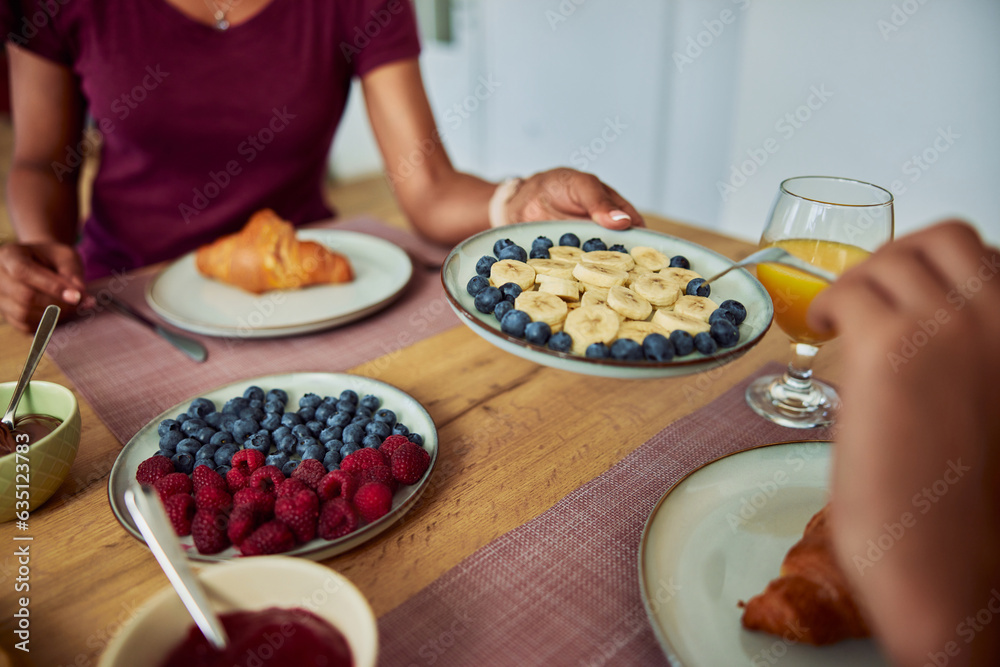 Close-up image of people having a healthy breakfast with berries, raspberries, and bananas.