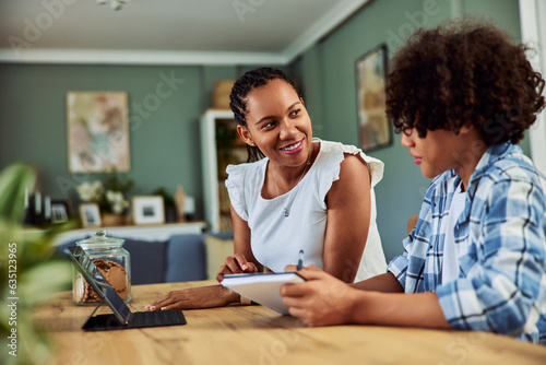 Smiling mother helping her son with assignments.