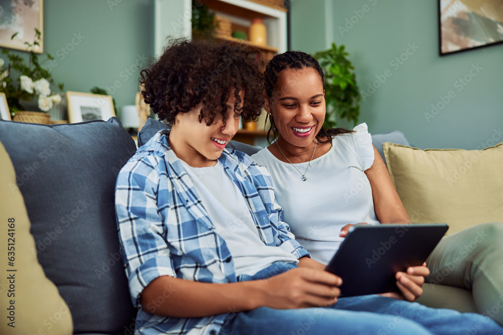 Fototapeta premium A smiling African mother and her son watching a movie on a digital tablet.