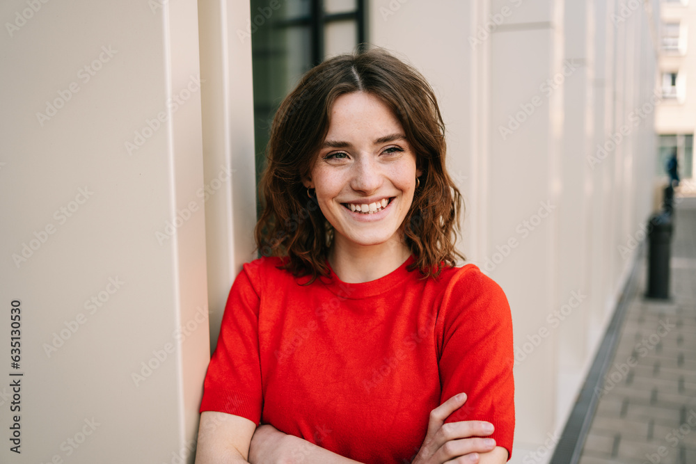 Young Woman in Red Sweater Leaning and Laughing by Modern Building Young Woman in Red Sweater Leaning and Laughing by Modern Building