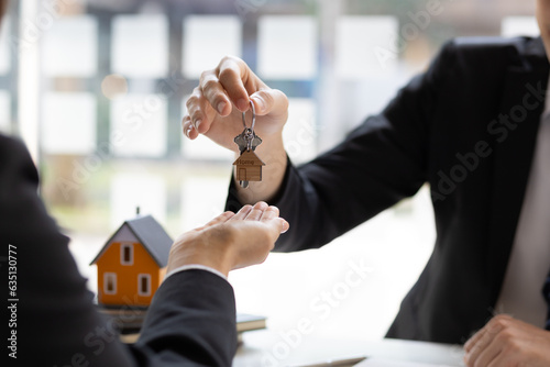 Real estate agent hands over the house keys to a homebuyer after the purchase agreement has been signed.