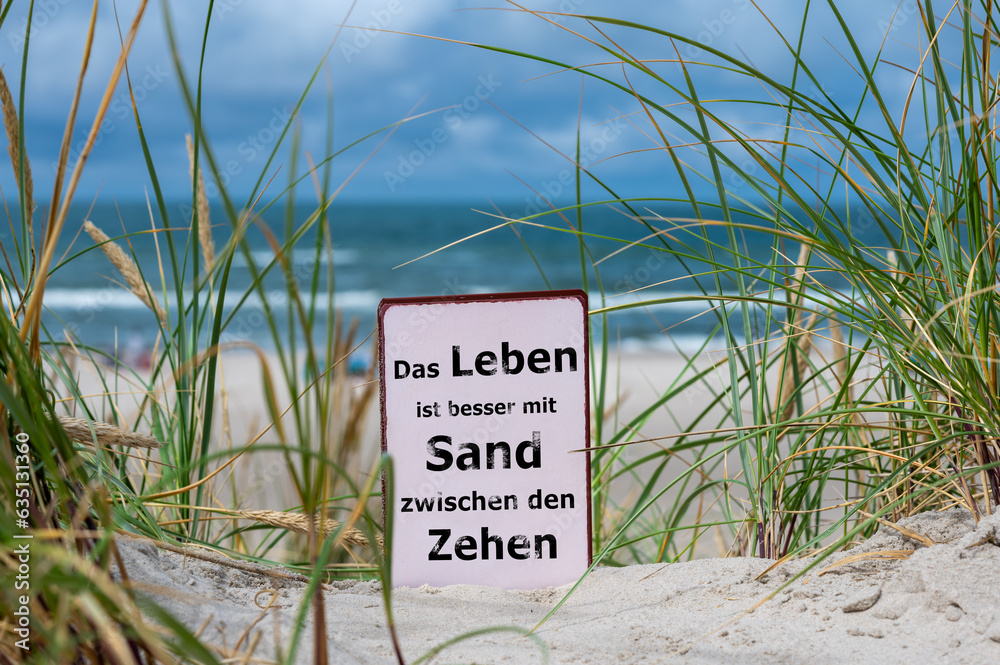 Φωτογραφία The German slogan 'das Leben ist besser mit Sand zwischen den Zehen' (life is better with Sand between the toes) in the sand dunes at the beach