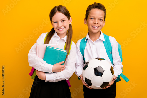 Photo of two lovely schoolkids prepare for school year hold soccer ball textbooks isolated on bright color background