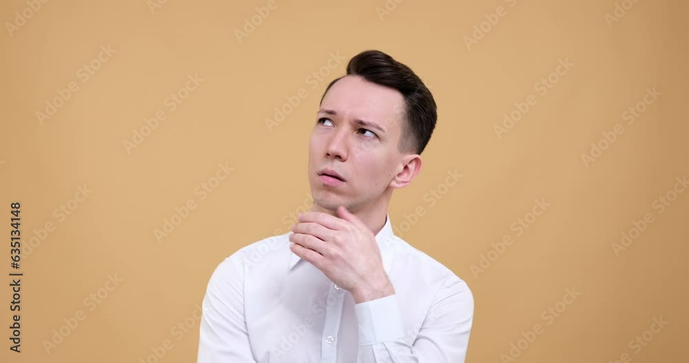 Caucasian man stands against a soothing beige background. His thoughtful gaze wanders into the depths of his thoughts, navigating the vast landscapes of his mind. Caucasian man stands against a soothing beige background. His thoughtful gaze wanders into the depths of his thoughts, navigating the vast landscapes of his mind.
