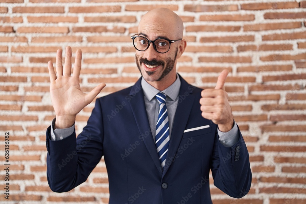 Bald man with beard wearing business clothes and glasses showing and pointing up with fingers number six while smiling confident and happy. Bald man with beard wearing business clothes and glasses showing and pointing up with fingers number six while smiling confident and happy.