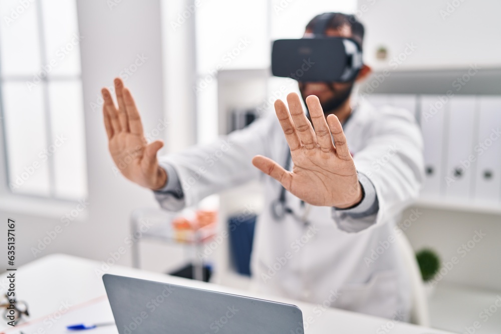 Young hispanic man doctor using virtual reality glasses at clinic
