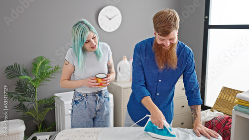 Man and woman couple smiling confident ironing clothes drinking coffee at laundry room