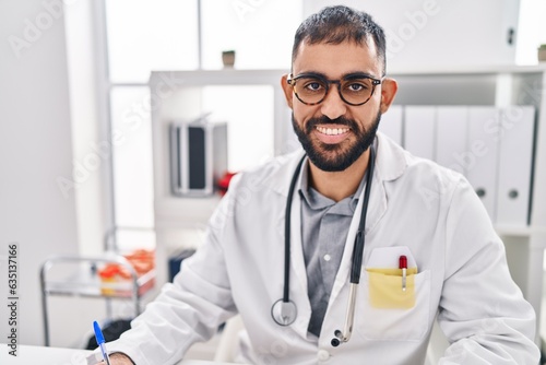 Young hispanic man doctor smiling confident standing on table at clinic
