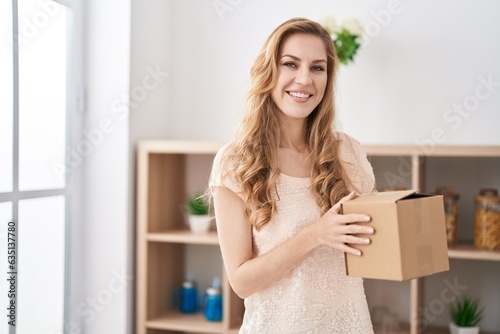 Young blonde woman smiling confident holding package at home