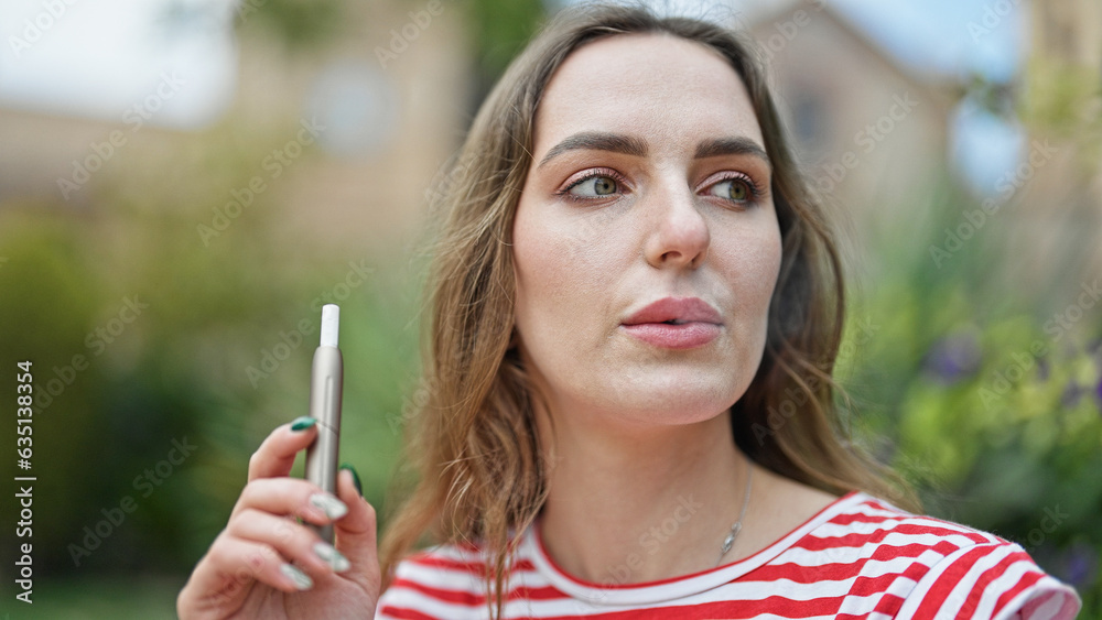 Young blonde woman smoking vaper at park Young blonde woman smoking vaper at park