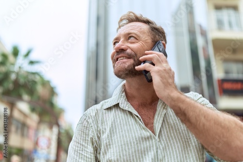 Middle age man smiling confident talking on the smartphone at street