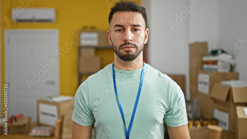 Young arab man volunteer standing with serious face at charity center