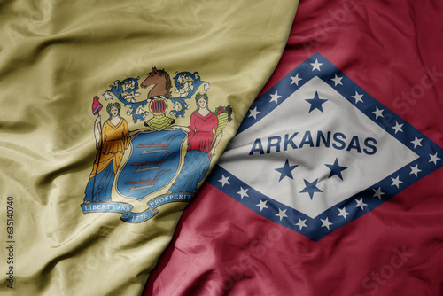 big waving colorful national flag of arkansas state and flag of new jersey state .