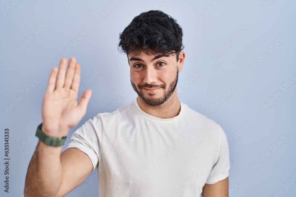 Hispanic man with beard standing over white background waiving saying hello happy and smiling, friendly welcome gesture Hispanic man with beard standing over white background waiving saying hello happy and smiling, friendly welcome gesture