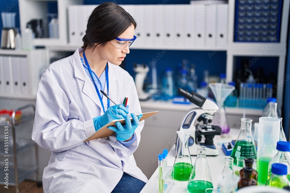 Young woman scientist writing on notebook at laboratory Young woman scientist writing on notebook at laboratory