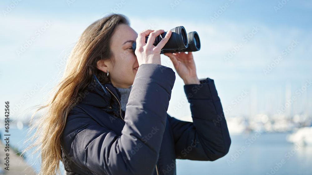 Young caucasian woman smiling confident using binoculars at seaside Young caucasian woman smiling confident using binoculars at seaside