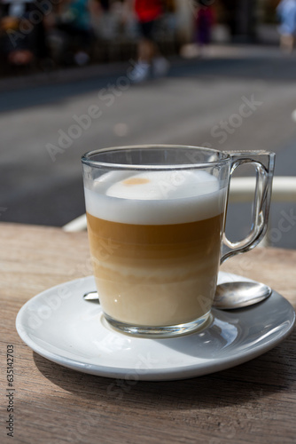 White cup of coffee latte served in outdoor cafe in France