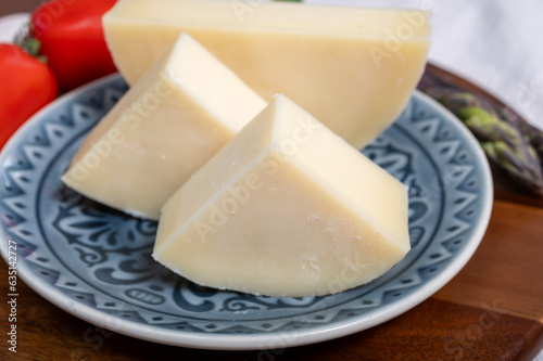 Italian cheese, Provolone dolce cow cheese from Cremona served with olive bread and tomatoes close up photo