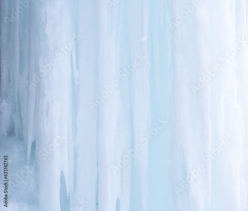 Frozen waterfalls on rocks with icicles in Iceland. Moss in ice. Spring warming, melting ice, dripping water of melted icicles.