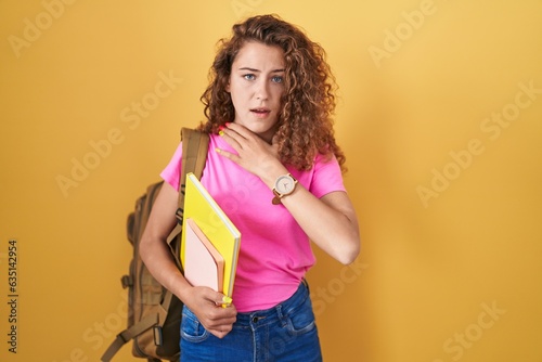 Young caucasian woman wearing student backpack and holding books cutting throat with hand as knife, threaten aggression with furious violence