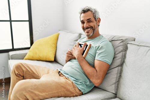 Middle age grey-haired man hugging picture sitting on sofa at home © Krakenimages.com