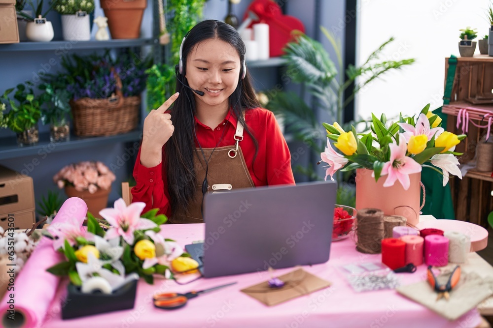 Young asian woman working at florist shop doing video call smiling happy pointing with hand and finger